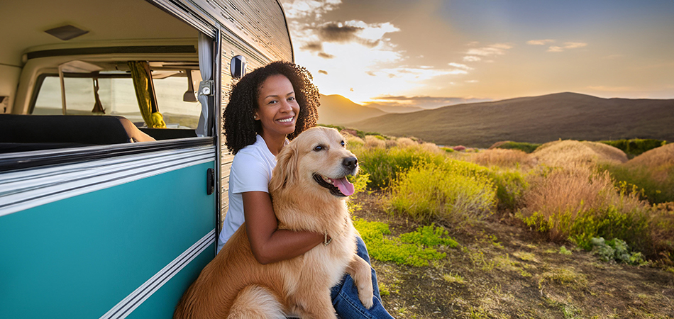 Lady with her dog sitting on the side of her camper RV, in the mountain